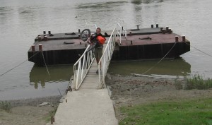 Zach carrying his trike over a narrow ferry ramp