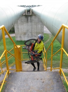 Zach carries his trike up the stairs on the pipeline bridge
