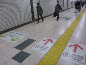 Floor of Tokyo subway hallway, showing you which direction to walk on which side of the hallway